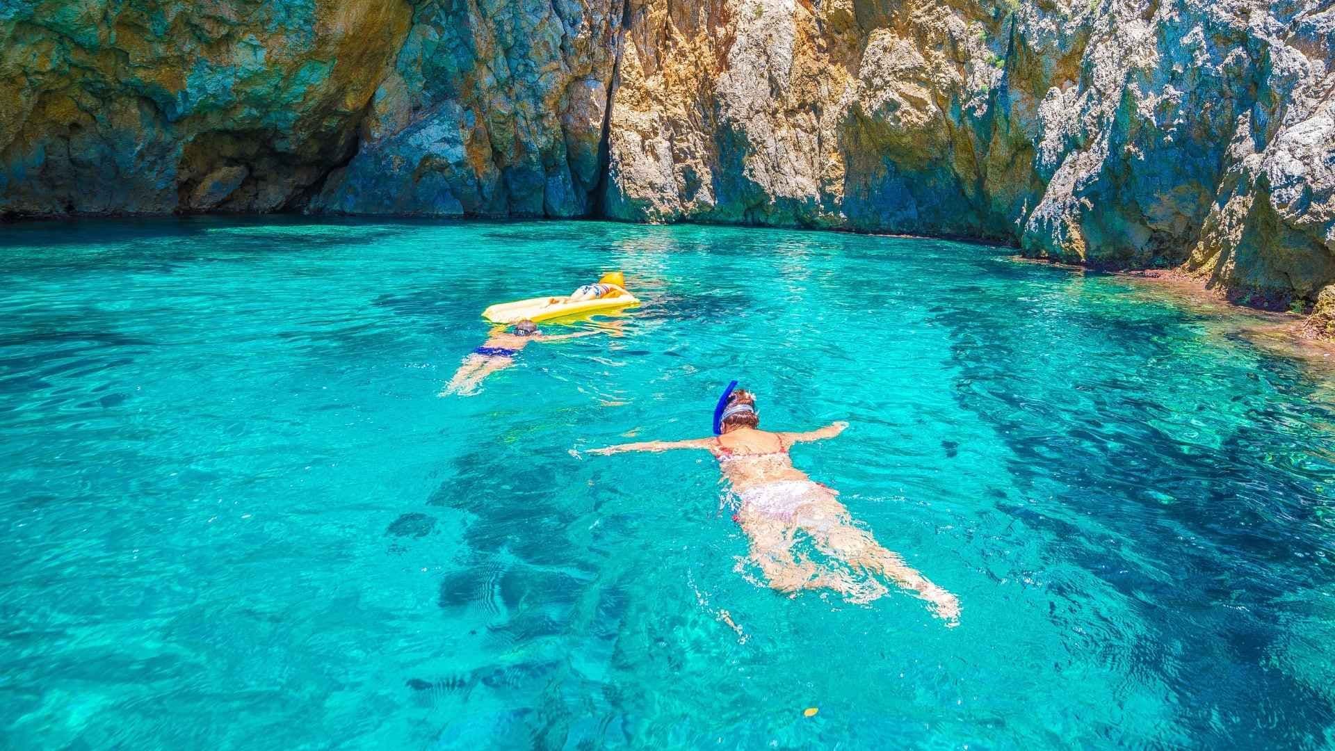 two people floating in the blue water greece