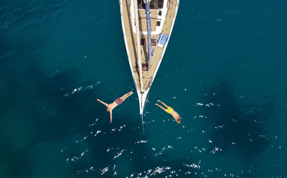 two people diving in water from bow